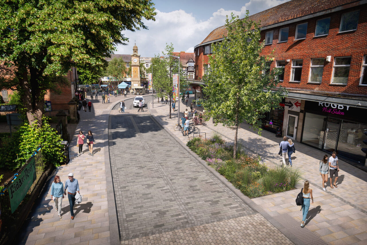 Artist's impression of a town centre street looking towards the Clock Tower, with wide stone paving, a block-paved carriageway, new trees and planting, and people walking and cycling.