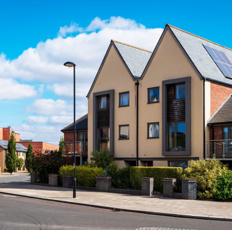 A modern three-storey block of flats with pitched gables.