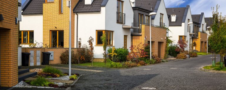 A street of new homes with front gardens and mixed brick and timber cladding.
