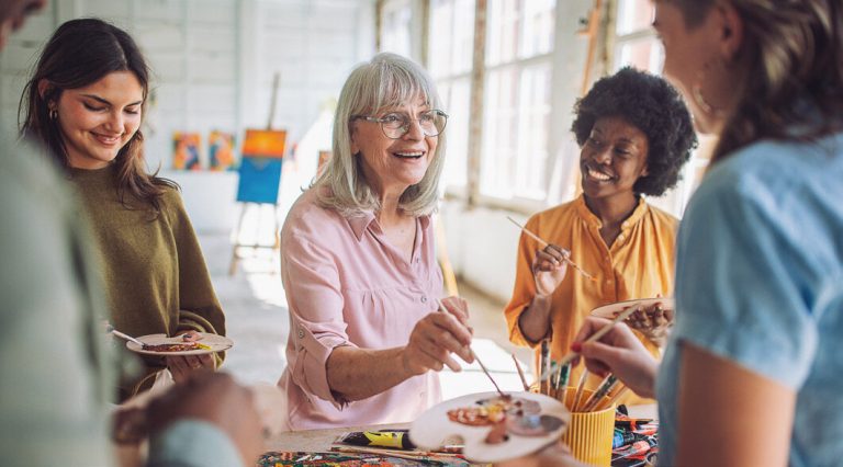 Women sharing food and laughing in a bright community space.