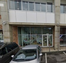 The empty ground-floor unit, with a glazed shopfront and cars parked outside.