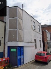 The rear of the building on Drury Lane, a plain rendered wall with a blue door.