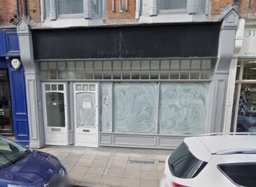 An empty shop with a grey shopfront and frosted windows.