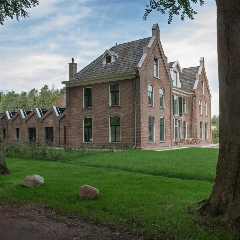 A large Victorian brick house with gables, set in open lawns.