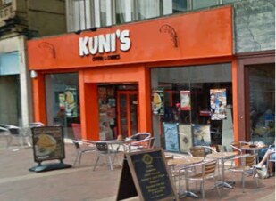The shopfront before the grant, painted bright orange with a café sign and tables outside.