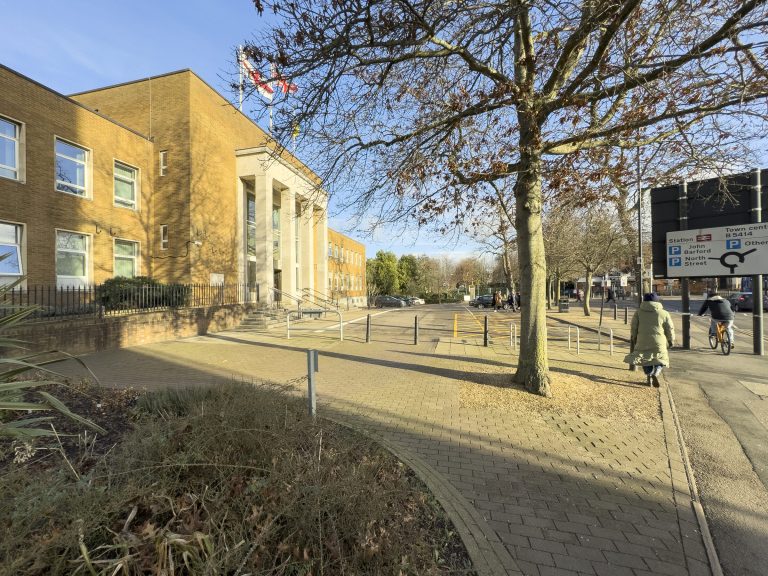 Rugby Town Hall seen from the corner of the site, with a paved path and trees.