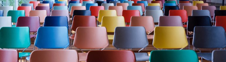 Rows of brightly coloured chairs set out in an events hall.